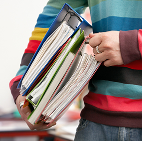 Student holding books and binders under their arm